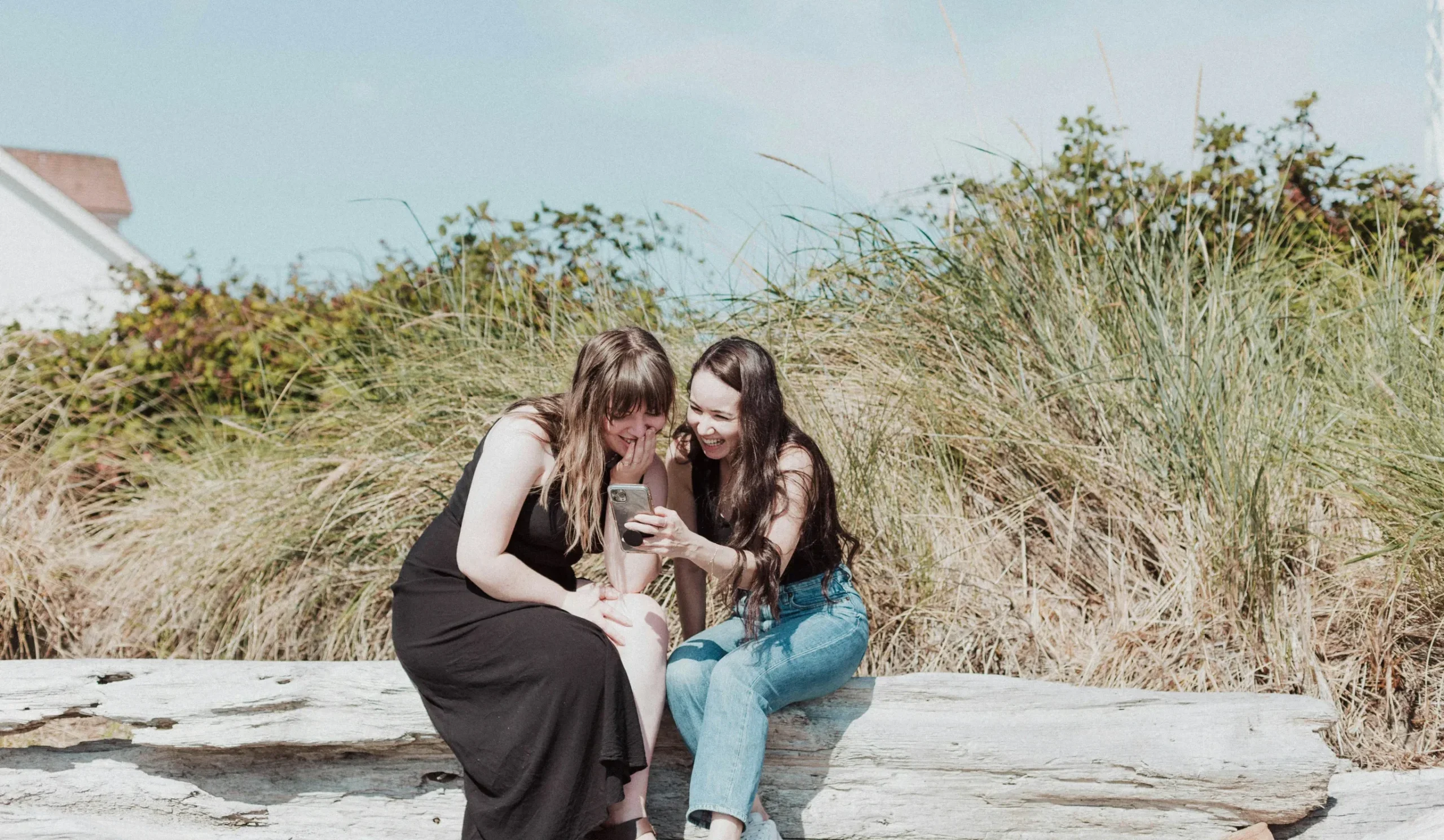two girls on the beach booking reservations with their phone